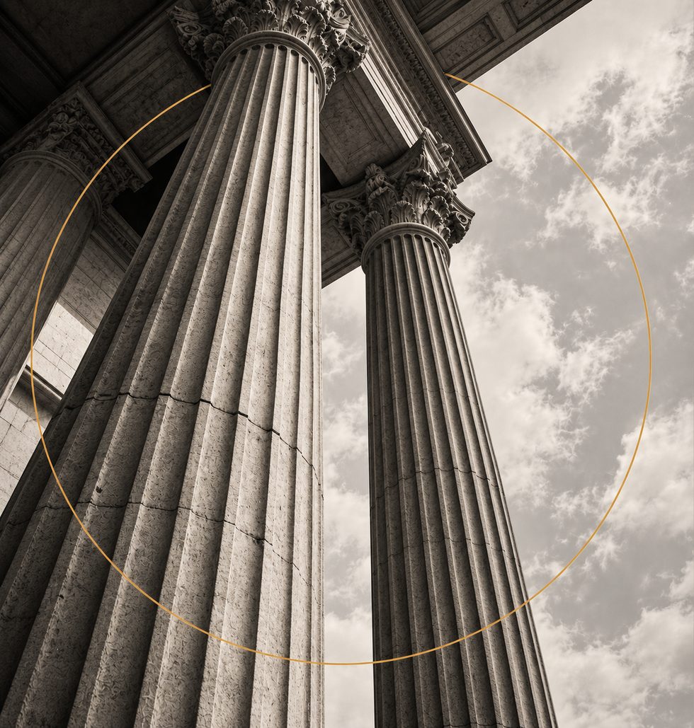Classical stone columns against the sky, framed by a thin gold ring